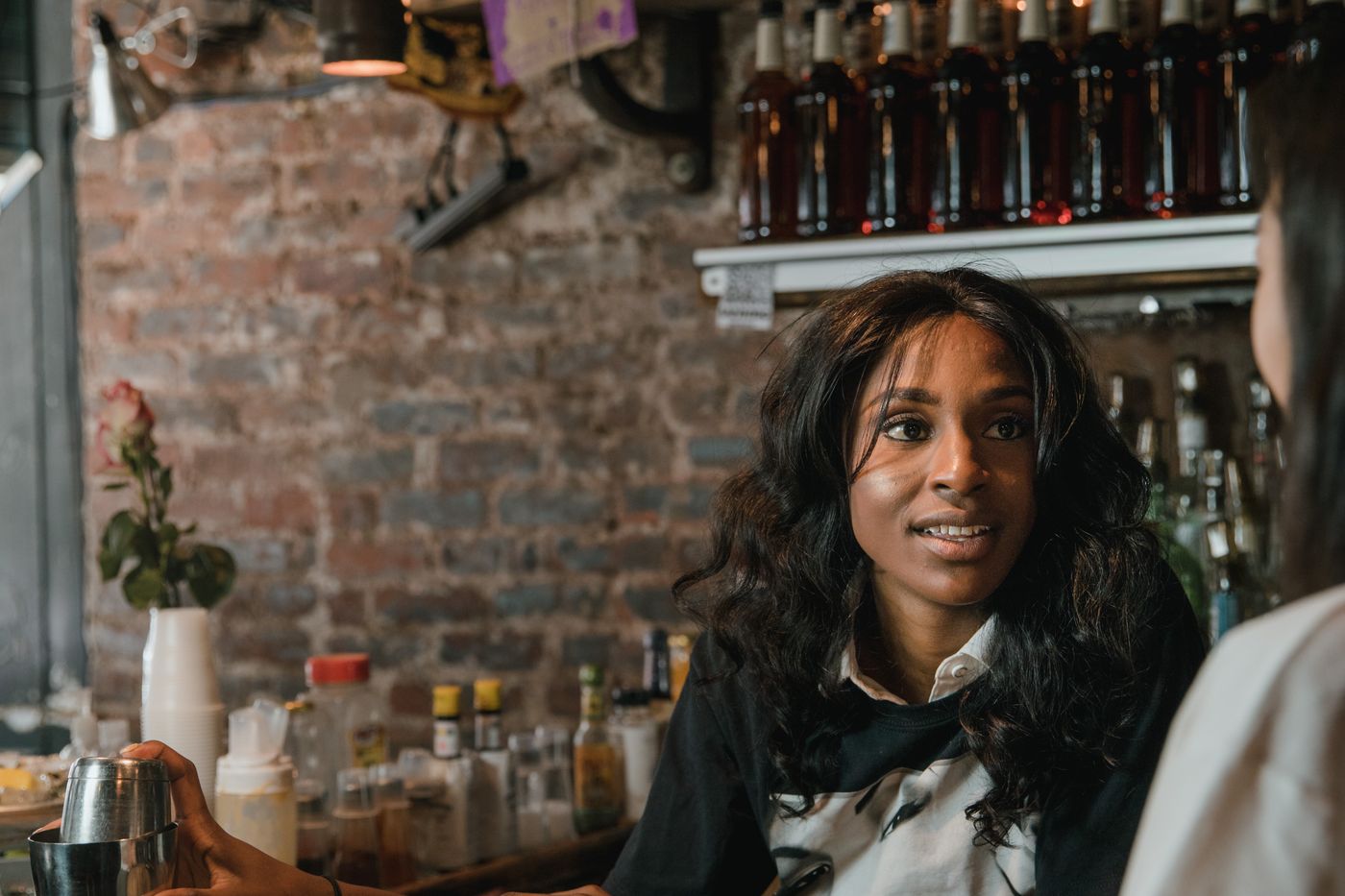 A bartender talking with a guest at the bar counter of a neighborhood restaurant, the relationship that produces repeat visits